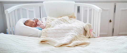 baby in cot next to bed