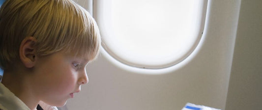 A young boy gazes out the window of an airplane.