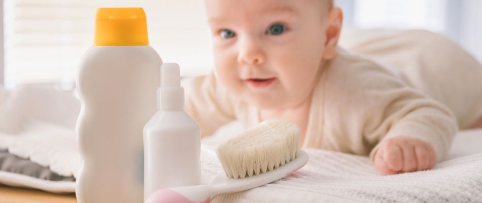 a baby lying on their front looking at skin products and a hairbrush