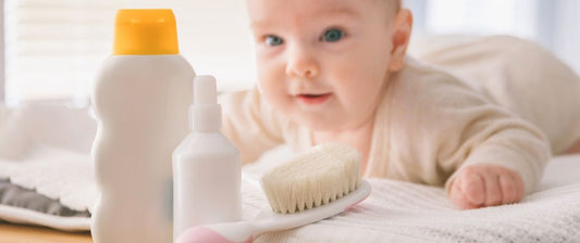 a baby lying on their front looking at skin products and a hairbrush