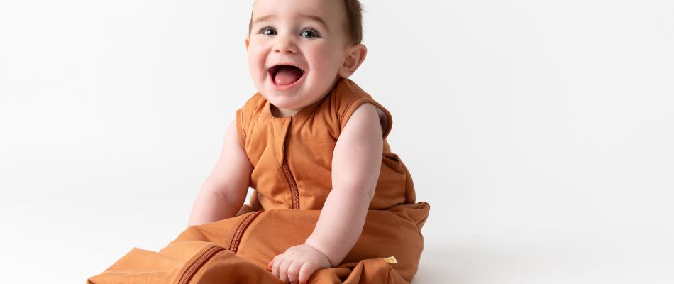 A smiling baby in the muslin sleeping bag