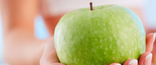 A close-up of a hand holding a vibrant green apple, symbolizing healthy eating and its benefits for fertility.