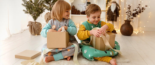 Two young children, joyfully engaged in opening Christmas gifts. 