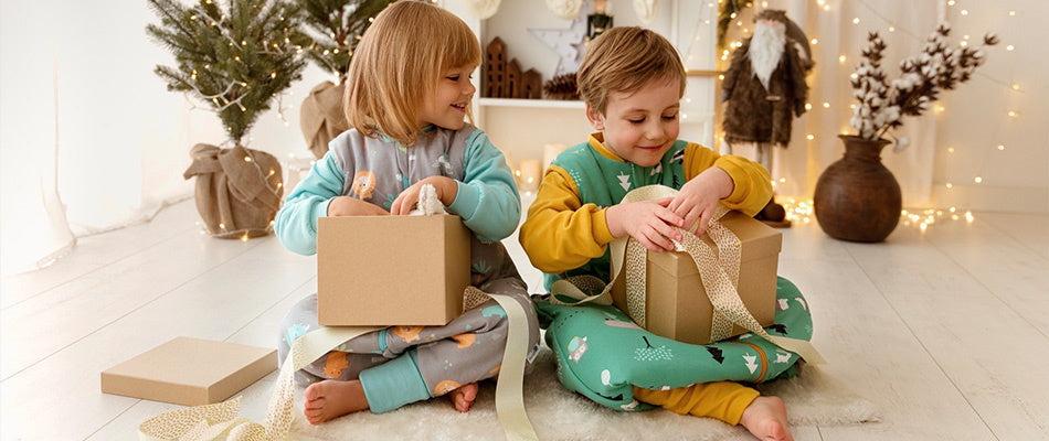 Two young children, joyfully engaged in opening Christmas gifts. 