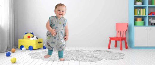  A toddler stands smiling in a colorful nursery, surrounded by toys and a vibrant red chair.