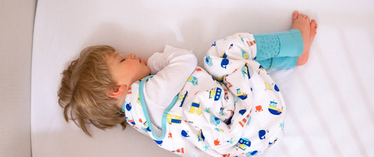 A toddler sleeps peacefully in a colorful sleeping bag, showcasing a relaxed and secure bedtime environment.