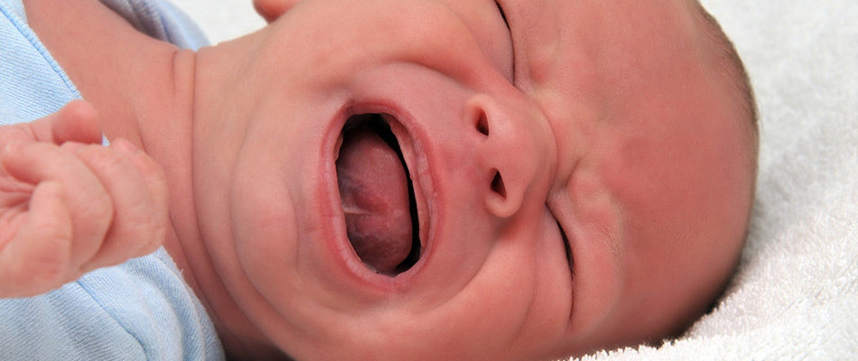  A close-up of a newborn crying intensely, capturing a moment of discomfort or need for care, with visible details like the mouth and tiny hands.