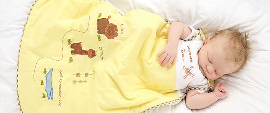 A baby sleeps under a yellow blanket embroidered with animal motifs, exuding peacefulness.