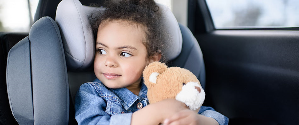 girl in car holding a teddy bear
