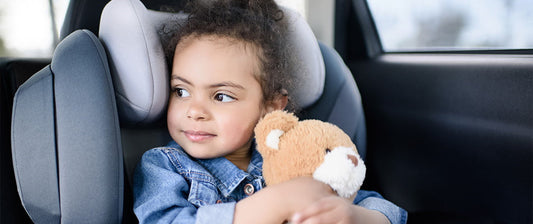 girl in car holding a teddy bear