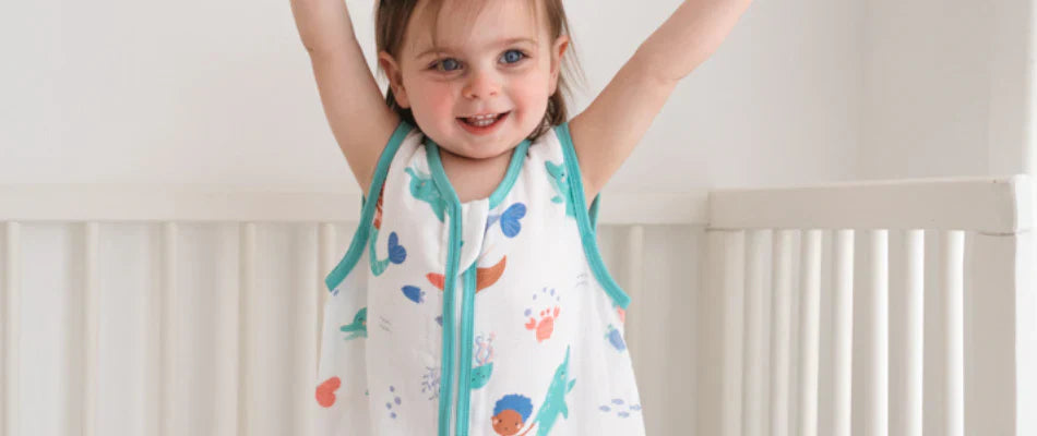 Toddler in a sleeping bag standing in bed