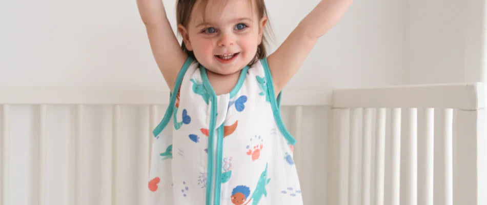 Toddler in a sleeping bag standing in bed
