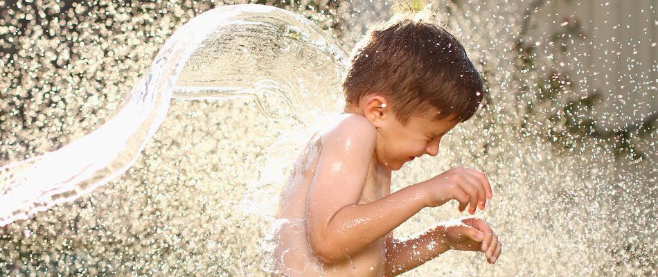 a joyful child engaged in a playful water fight, with water splashing around them