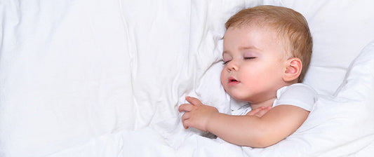  A toddler sleeps peacefully on a white bed, highlighting the restorative power of sleep during illness.